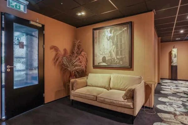 Zithoek met beige bank en kunst aan de muur in een sfeervolle gang aan de Oude Utrechtseweg.